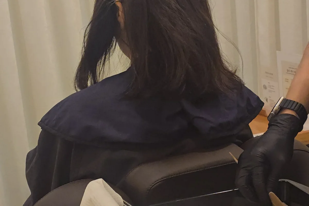 의자에 앉은 고객의 모발에 컬러 제품을 도포하는 스태프